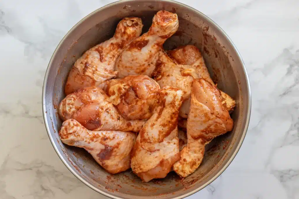 chicken drumsticks are covered with olive oil, tomato paste, and spices
