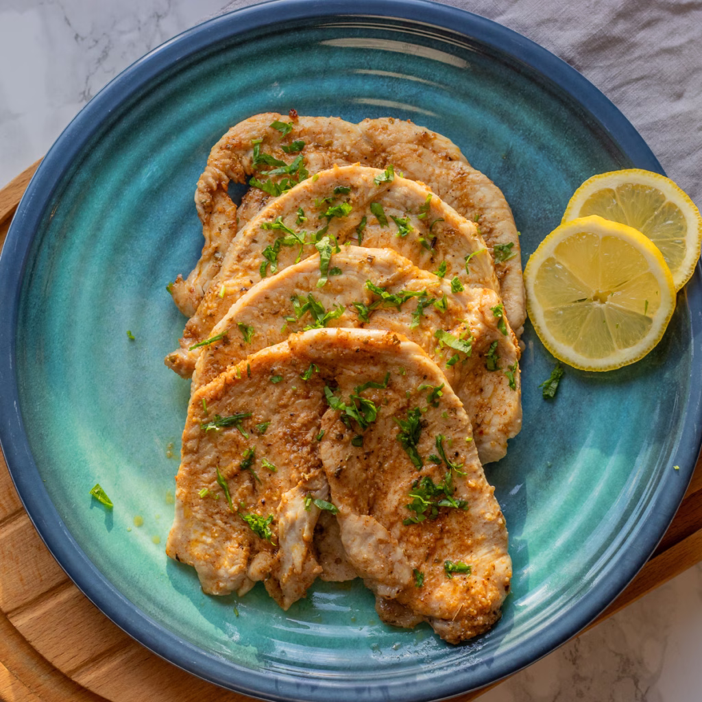 Air fryer turkey cutlets on a blue plate with lemon slices.